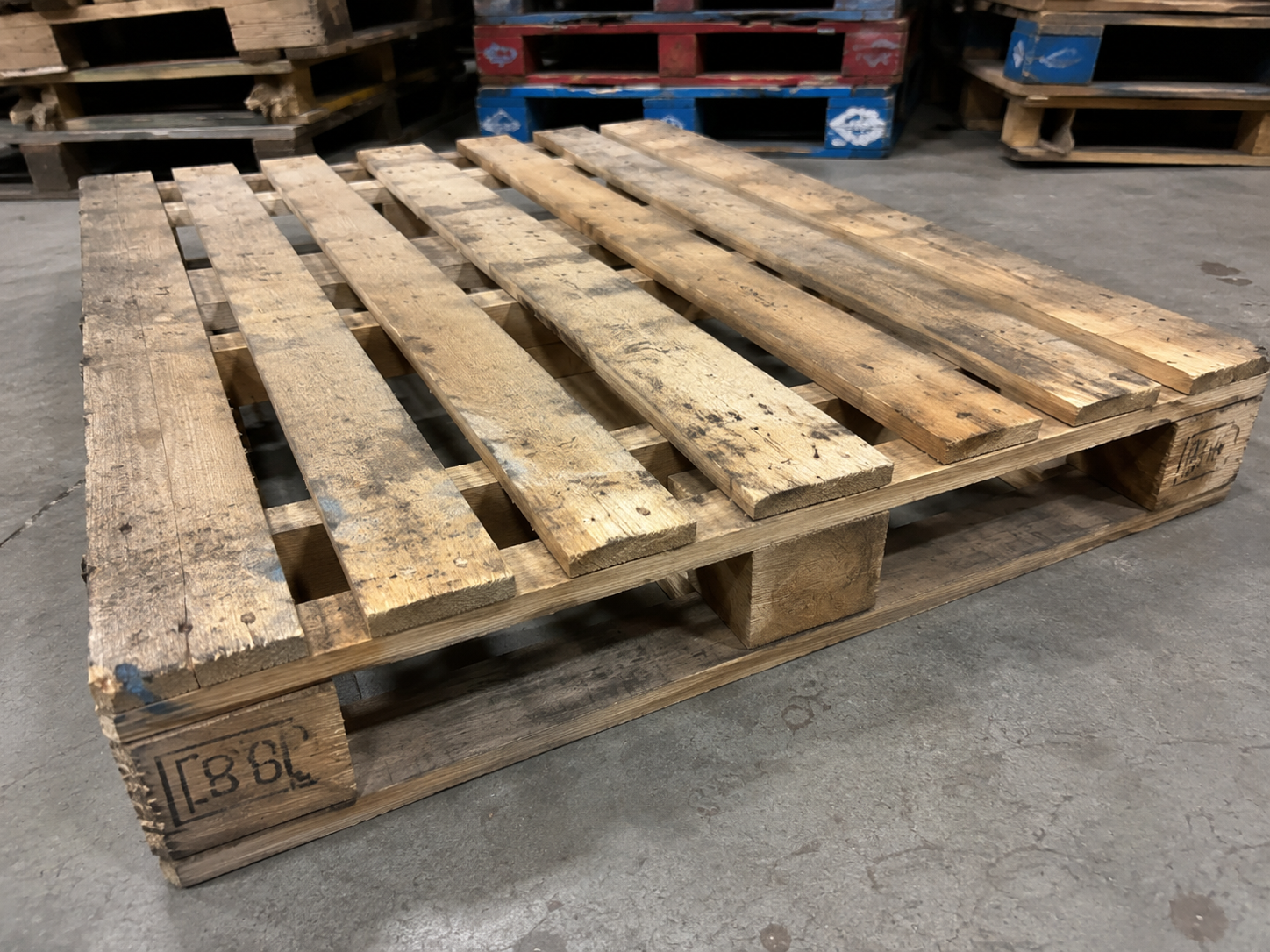 A repaired 48 by 40 reclaimed wood pallet on the warehouse floor
