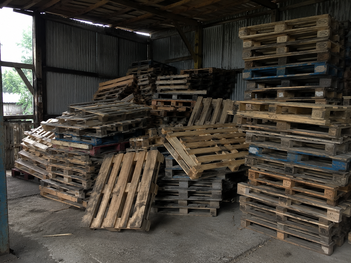 A large pile of reclaimed pallets in the shed awaiting sorting